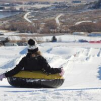 A person enjoys a thrilling ride down the snow-covered tubing lanes at soldier hollow nordic center in midway utah With bright winter skies fresh snow and sweeping views of the heber valley its a perfect spot for outdoor fun and adventure My local utah