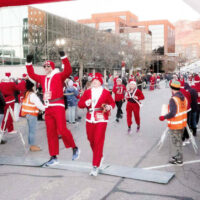 Cheerful participants in santa costumes jogging through ogdens festive downtown streets during the santa run My local utah