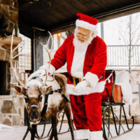 Santa claus greeting children next to live reindeer at gardner village My local utah