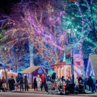 A panoramic view of ogdens christmas village - a perfect holiday date in utah - showcases numerous light displays holiday-themed houses and decorated trees all glowing against the winter night The vibrant scene is filled with holiday magic drawing visitors of all ages My local utah