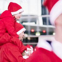 Family of runners standning on the sidelines watching runners cross the finish line in a holiday santa run in downtown ogden My local utah
