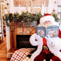 Santa claus dressed in his classic red suit with a fluffy white beard reading a christmas book to children aboard the north pole express at the heber valley railroad The my local utah