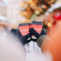 A couple enjoying the warm and inviting hot cocoa from the drink station at ogden winter market another fun holiday date idea in utah where couples can cozy up with seasonal drinks and treats My local utah