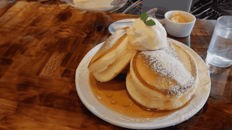 image of a close up on some delicious Japanese fluffy pancakes powdered with sugar and covered in sweet syrup