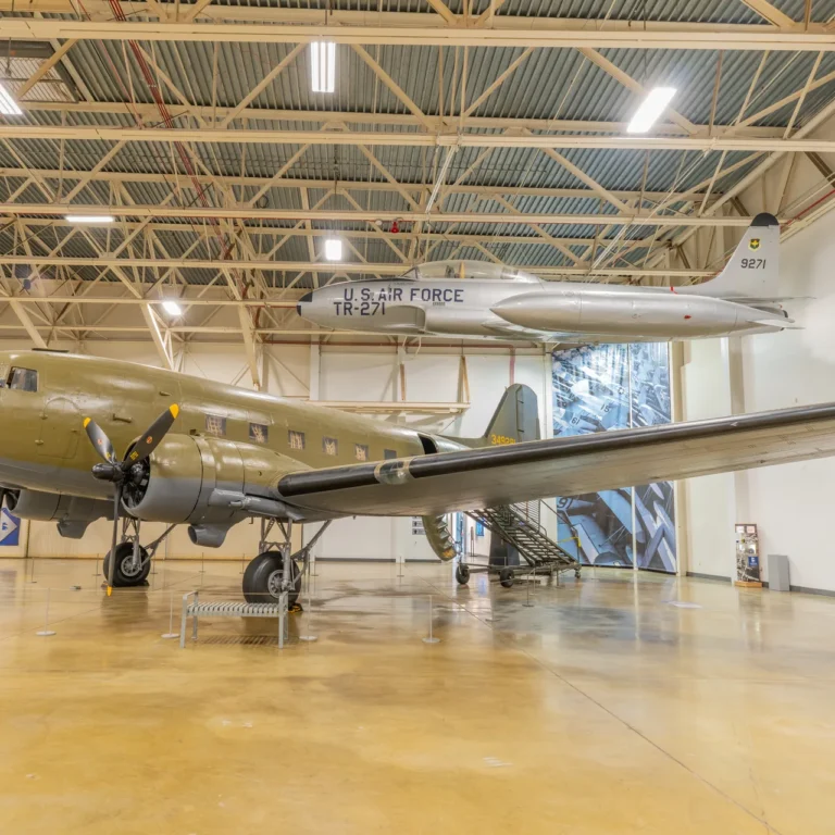 Inside a Hill Aerospace Museum gallery in Roy, Utah, with a C-47 Skytrain on the floor and a T-33 trainer suspended overhead